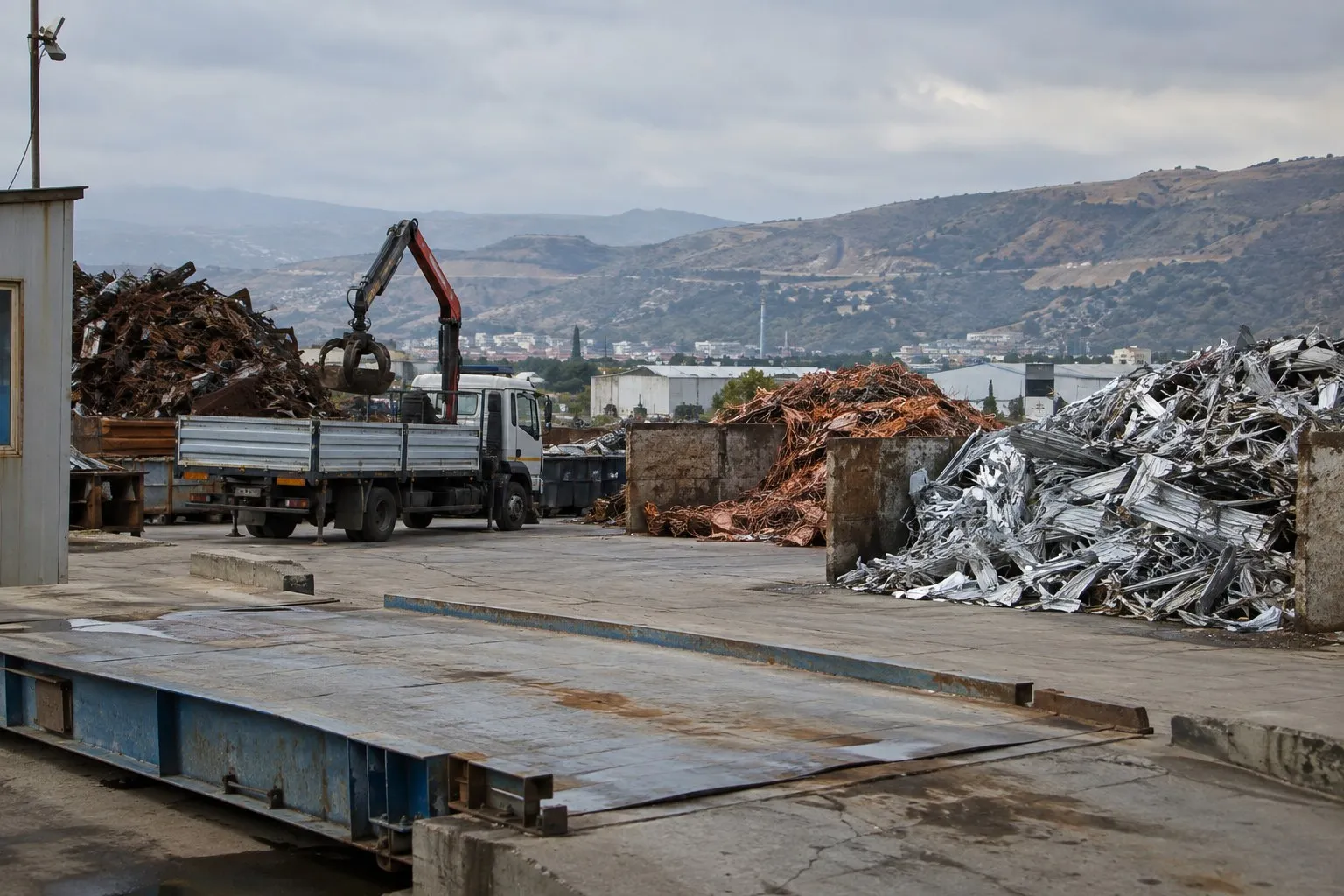 Tartı platformu, vinçli kamyon ve ayrı ayrı istiflenmiş bakır, alüminyum ve demir yığınlarıyla İzmir'de bir hurda sahası